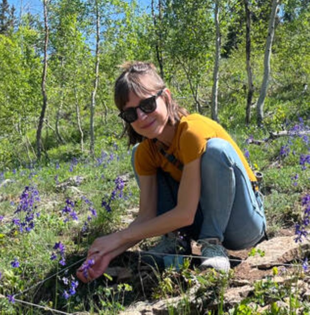 Amy Iler next to a blue/purple-flowered plant.